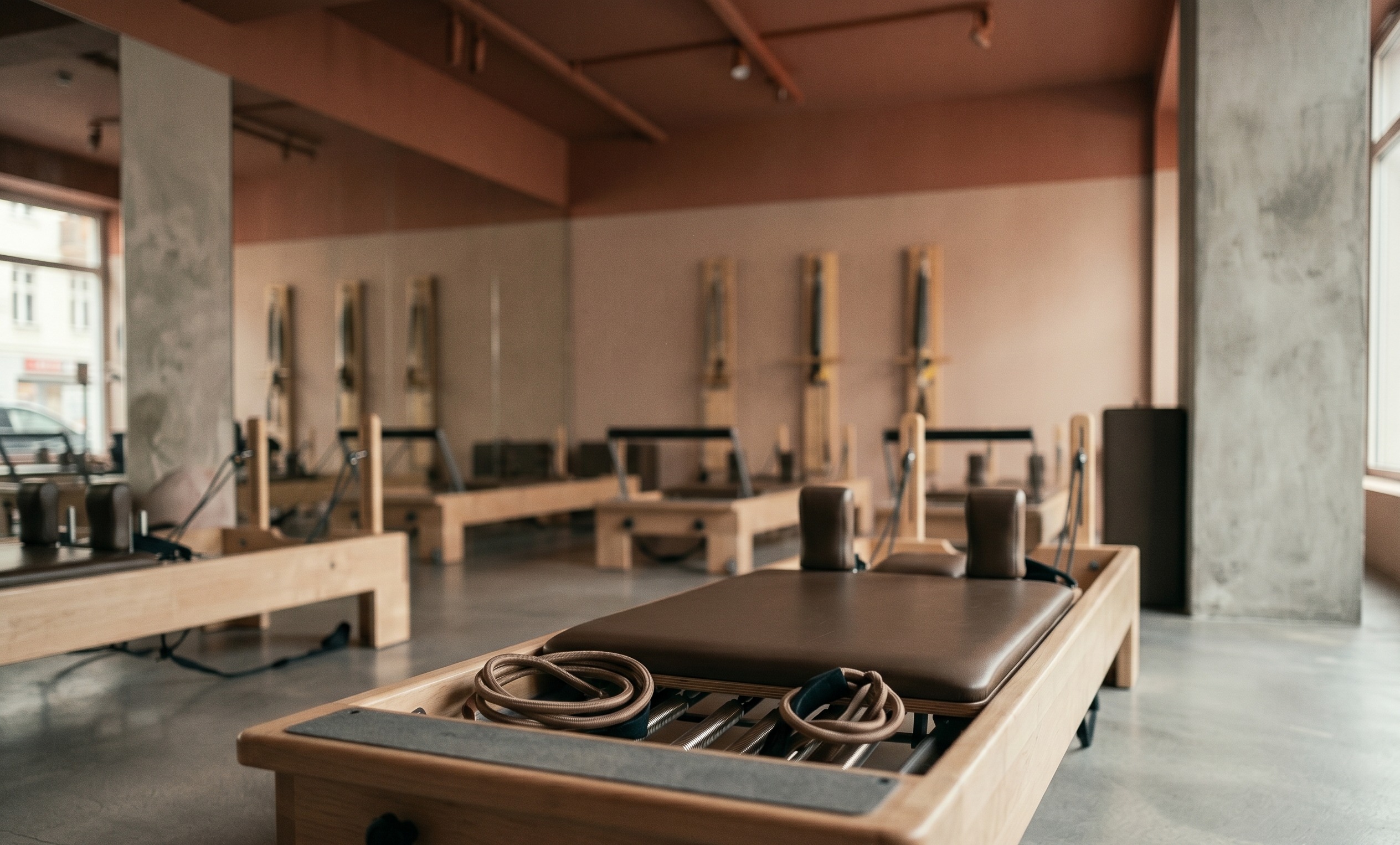 An empty, soft-lit Pilates reformer studio — beautiful, but lifeless.
